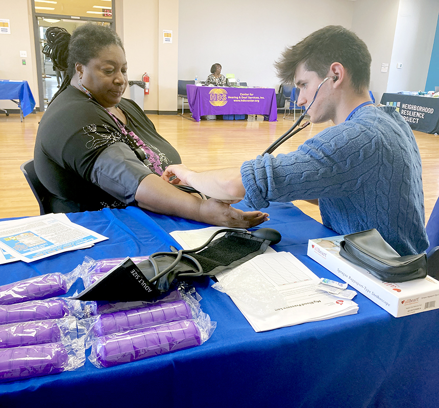 Peter Grandell (PS3) is taking the blood pressure of Stephanie White, program assistant for the Hill District Consensus Group