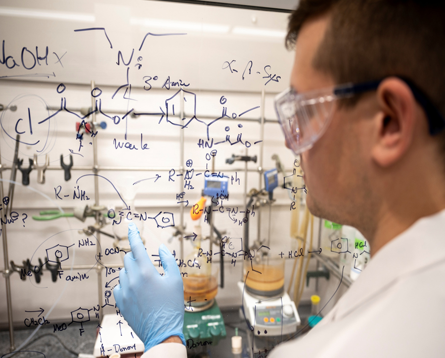 student writing on a clear board